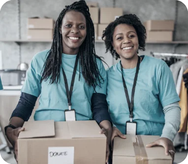Two volunteers smiling while holding donation boxes